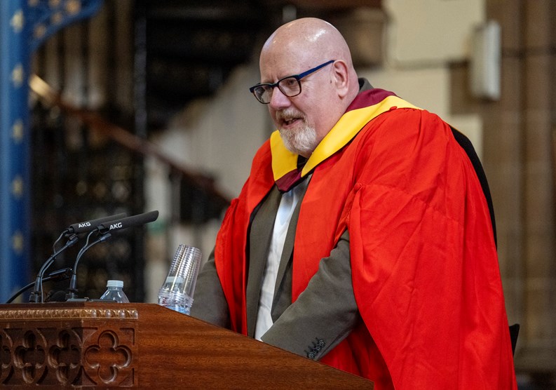 Man speaking into a microphone at a graduation