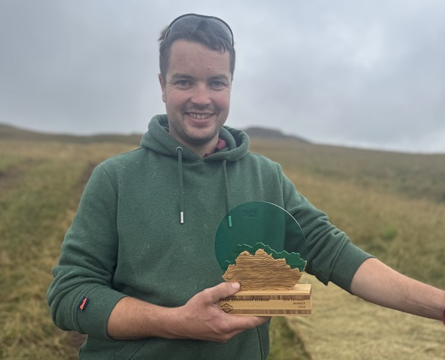 A man standing in a field holding an award