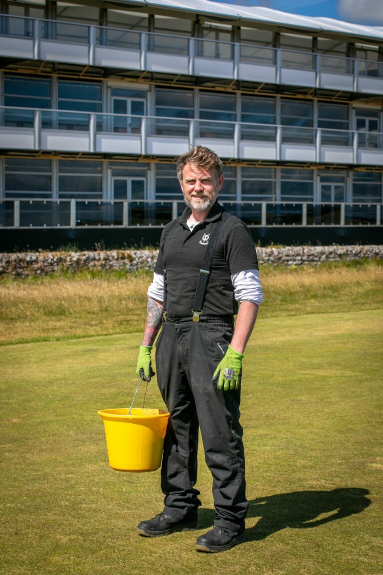 Man standing on a golf green in work clothes