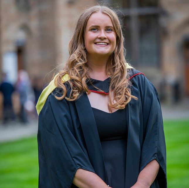 A girl standing wearing a graduate gown