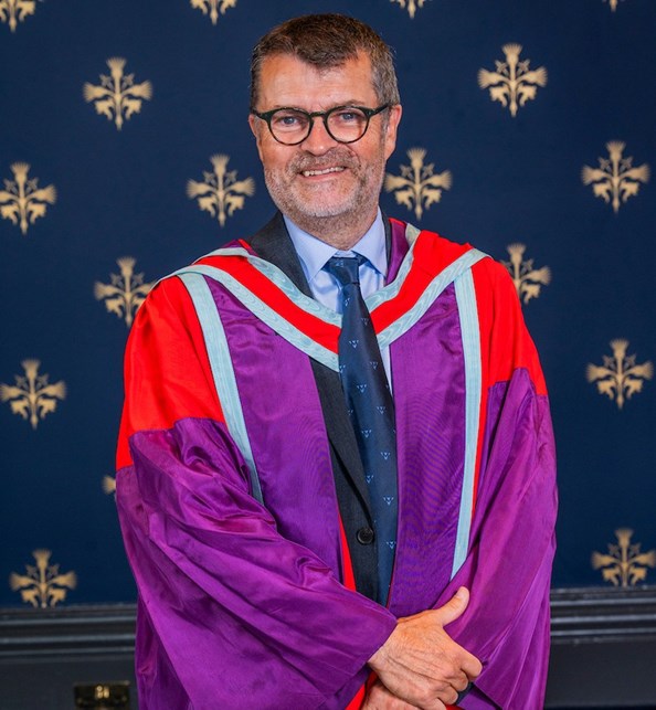 A man standing wearing a graduation gown