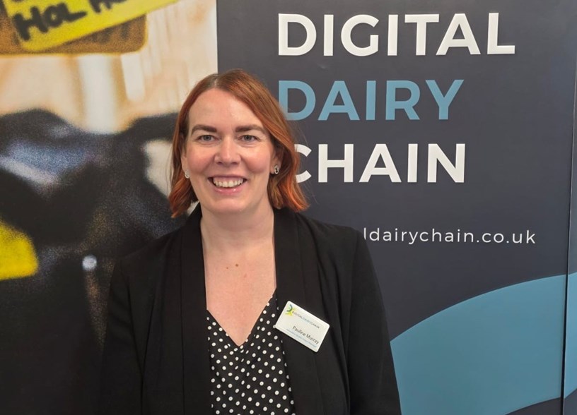 Woman stands in front of a sign that says 'Digital Dairy Chain' on it.