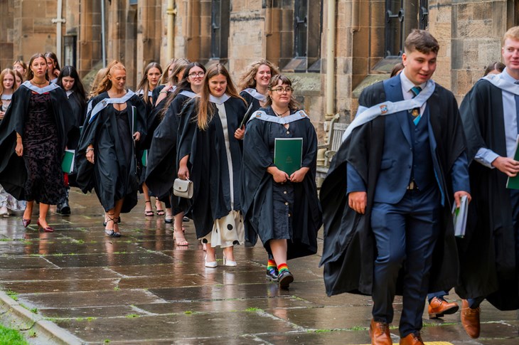 students wearing graduation gowns walking in a parade