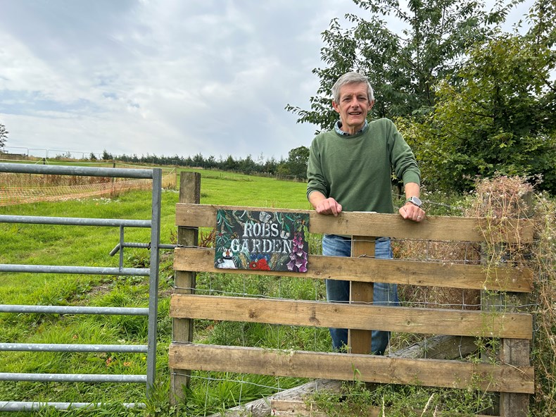Man on a farm standing behind a fence.