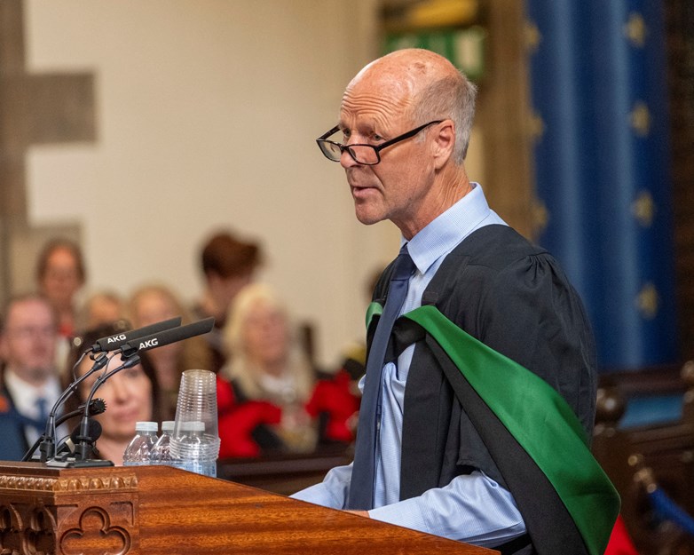 Man speaking into a microphone at a graduation